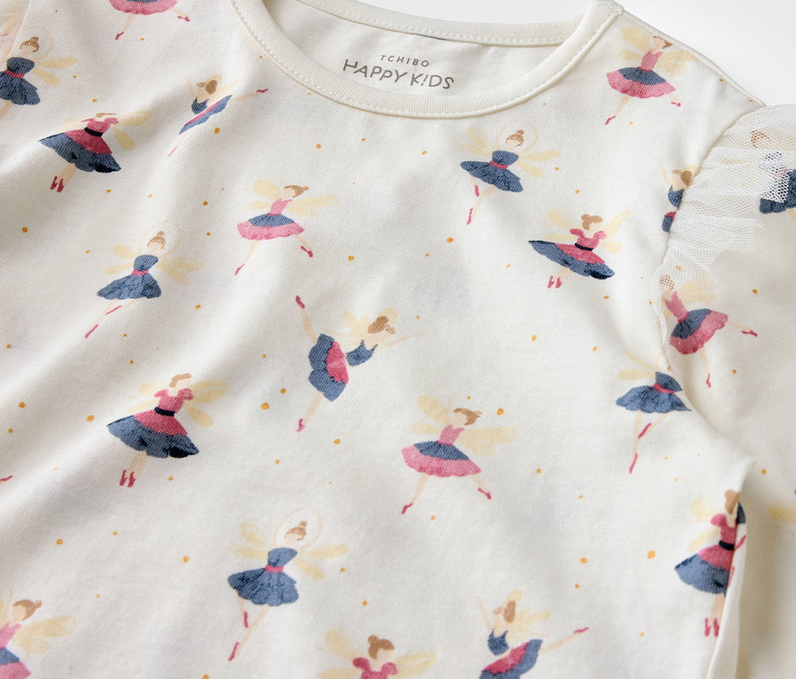Gros plan d'un t-shirt blanc imprimé de ballerines et de points dorés.
