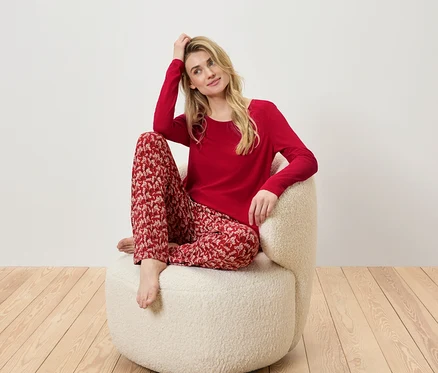 Blonde assise dans un fauteuil portant un pyjama rouge à motifs.