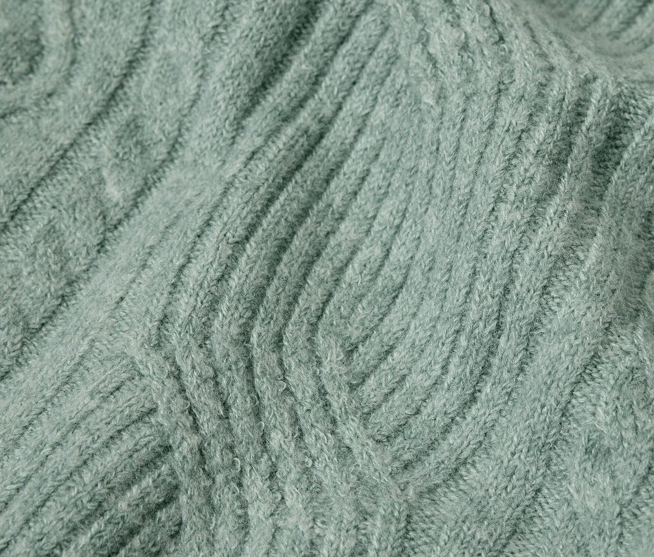 Gros plan sur la texture d'un pull en tricot de couleur vert sauge.