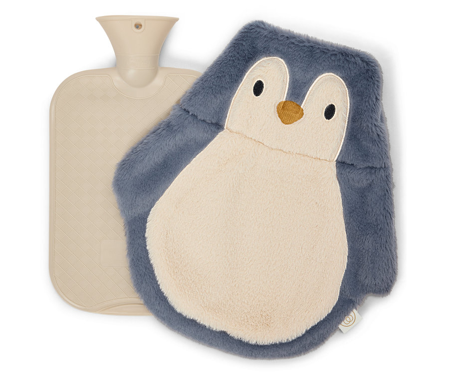 Une bouillotte beige est posée à côté d'une housse de bouillotte en forme de pingouin.