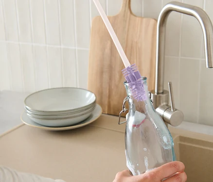 Une main nettoie une bouteille avec une brosse de nettoyage pour bouteilles.