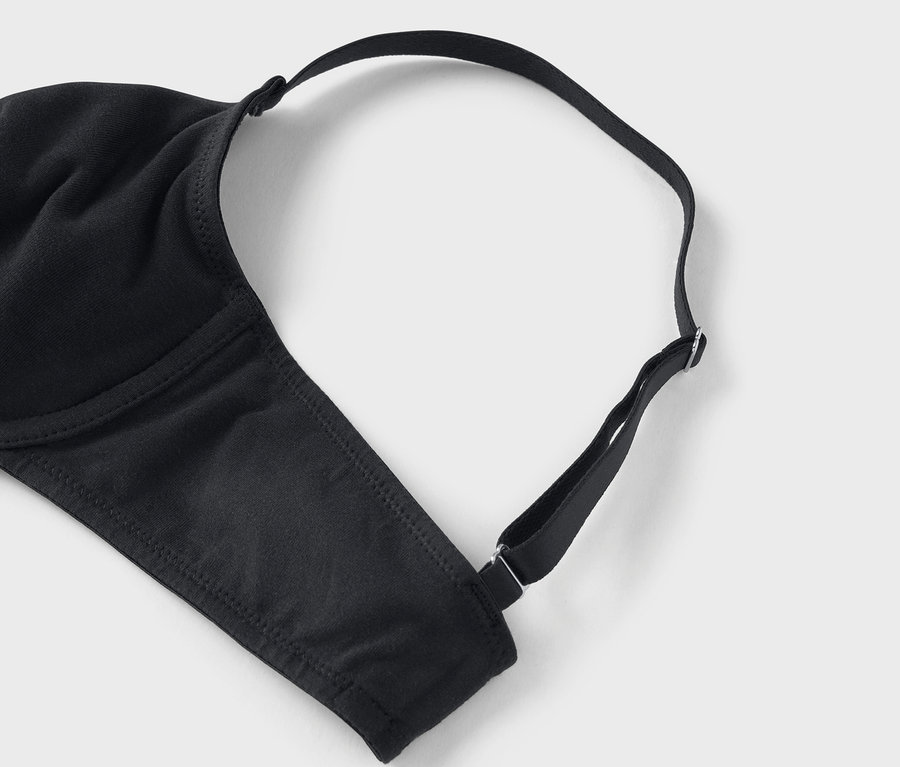 Gros plan d'un soutien-gorge noir avec bretelles réglables sur un fond gris.