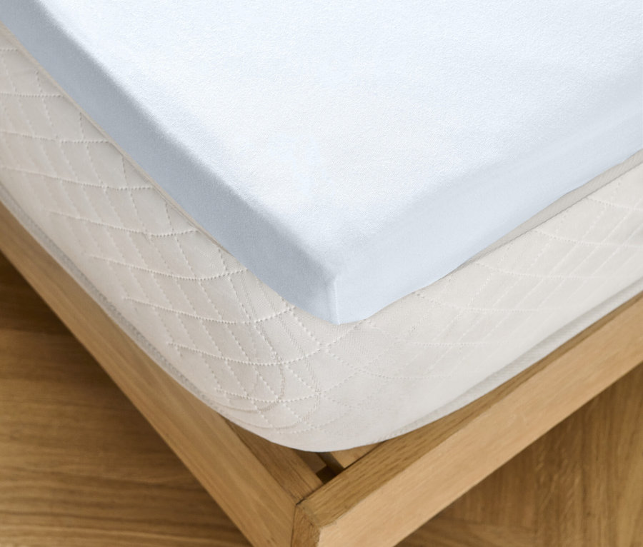 Drap-housse blanc sur un matelas avec un cadre de lit en bois.
