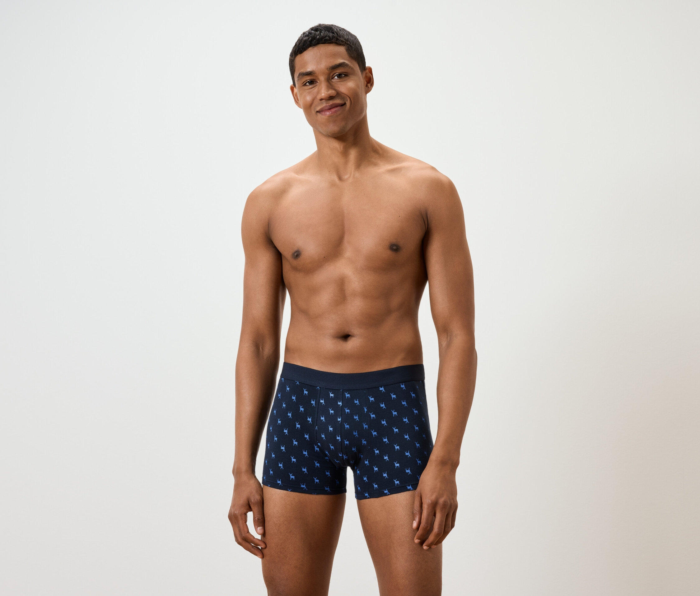 Homme posant sur fond blanc en caleçon boxer bleu à motifs.