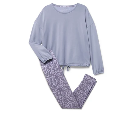 Un haut de pyjama bleu à manches longues et un pantalon à motif de feuilles sont posés sur un fond blanc.