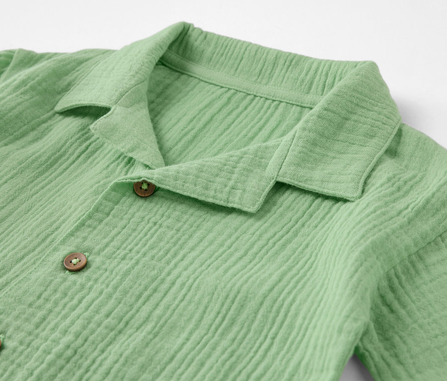 Gros plan sur une chemise en mousseline verte pour enfant avec col.