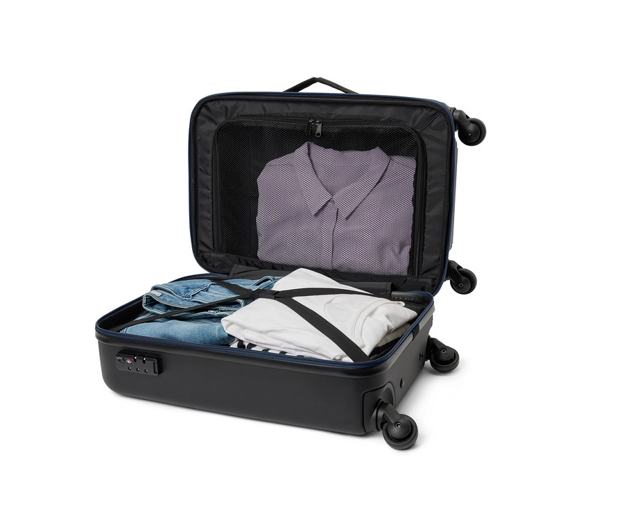 Une valise hybride noire ouverte de petite taille avec des vêtements à l'intérieur.