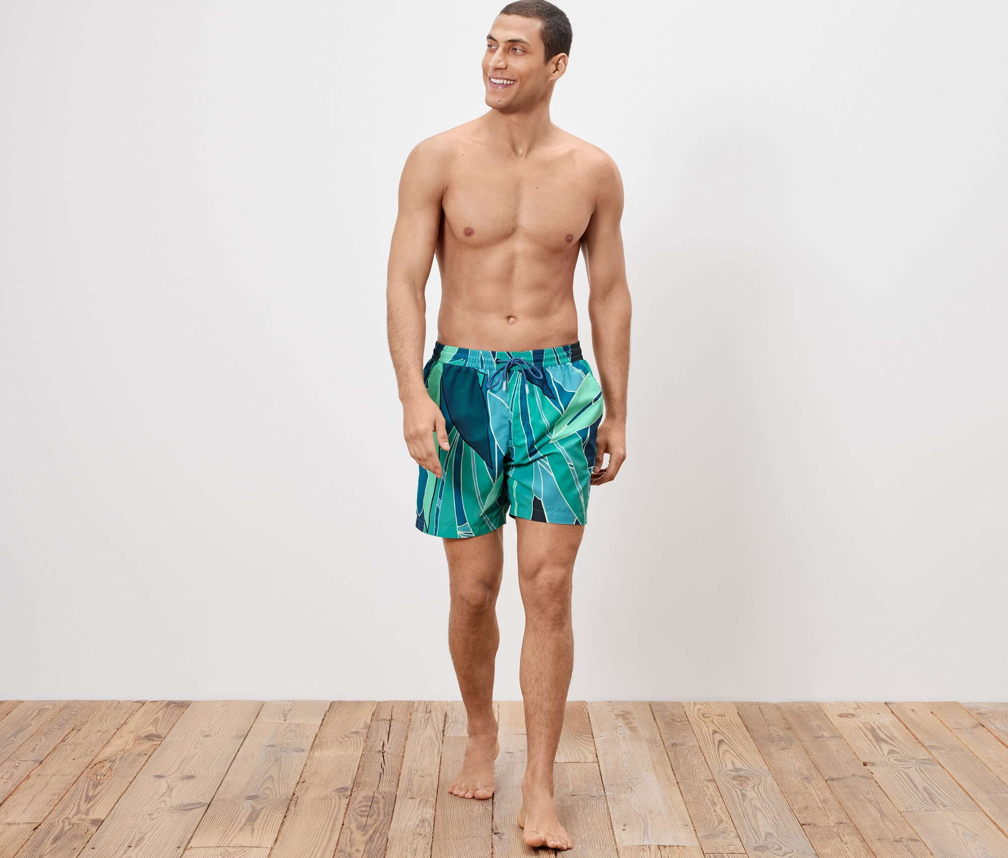 Un homme marche et porte un short de bain.