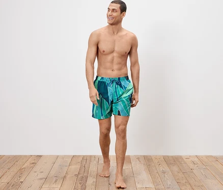 Un homme marche et porte un short de bain.