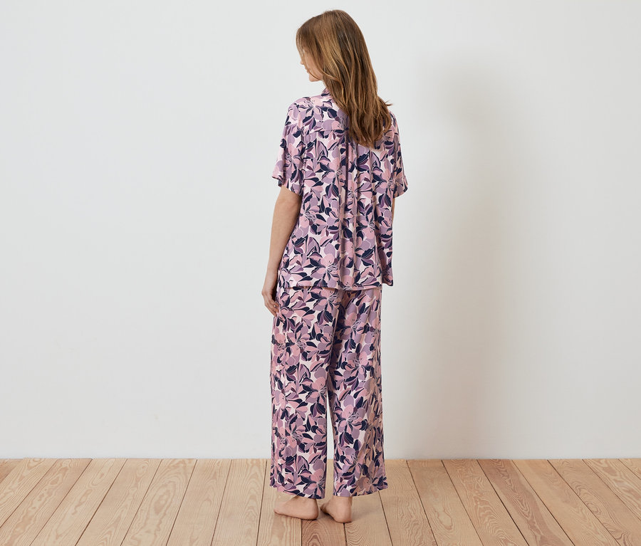 Une femme, vue de dos, porte un pyjama à fleurs.