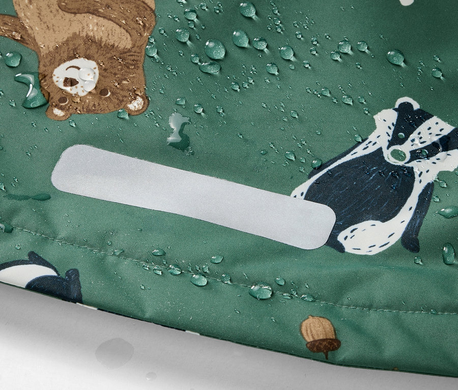 Détail d'une veste de pluie thermique pour enfant avec un motif d'animaux de la forêt et des gouttes d'eau.