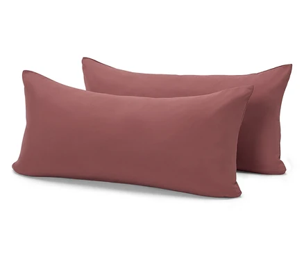 Deux oreillers rectangulaires couleur brique sont posés l'un sur l'autre sur un fond blanc.