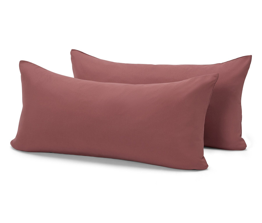 Deux oreillers rectangulaires couleur brique sont posés l'un sur l'autre sur un fond blanc.