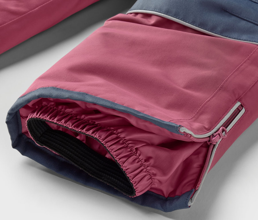 Gros plan sur le bas de pantalon d'une combinaison de ski 2 pièces pour enfants, rose et bleu.