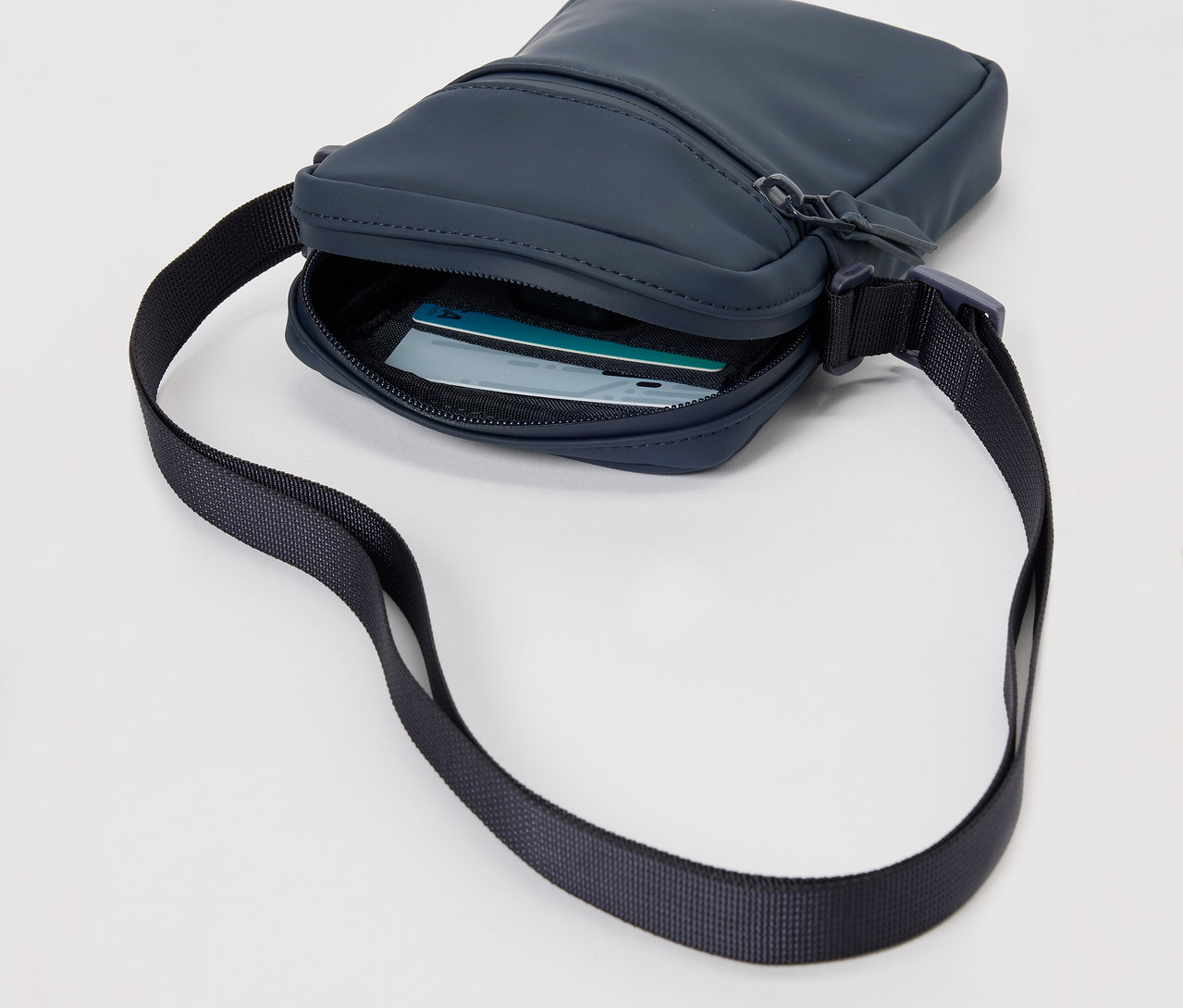 Sac à bandoulière de pluie bleu marine avec une sangle noire et des cartes à l'intérieur.