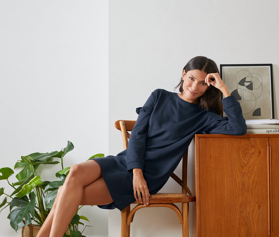 Femme assise sur une chaise portant une robe molletonnée.