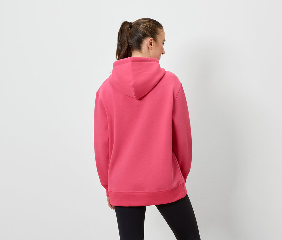 Une femme, vue de dos, porte un sweat à capuche rose et un legging noir.