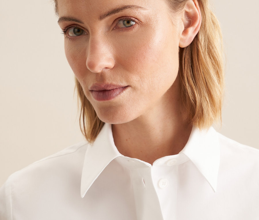 Portrait d'une femme blonde portant une blouse blanche à manches courtes Seidensticker.