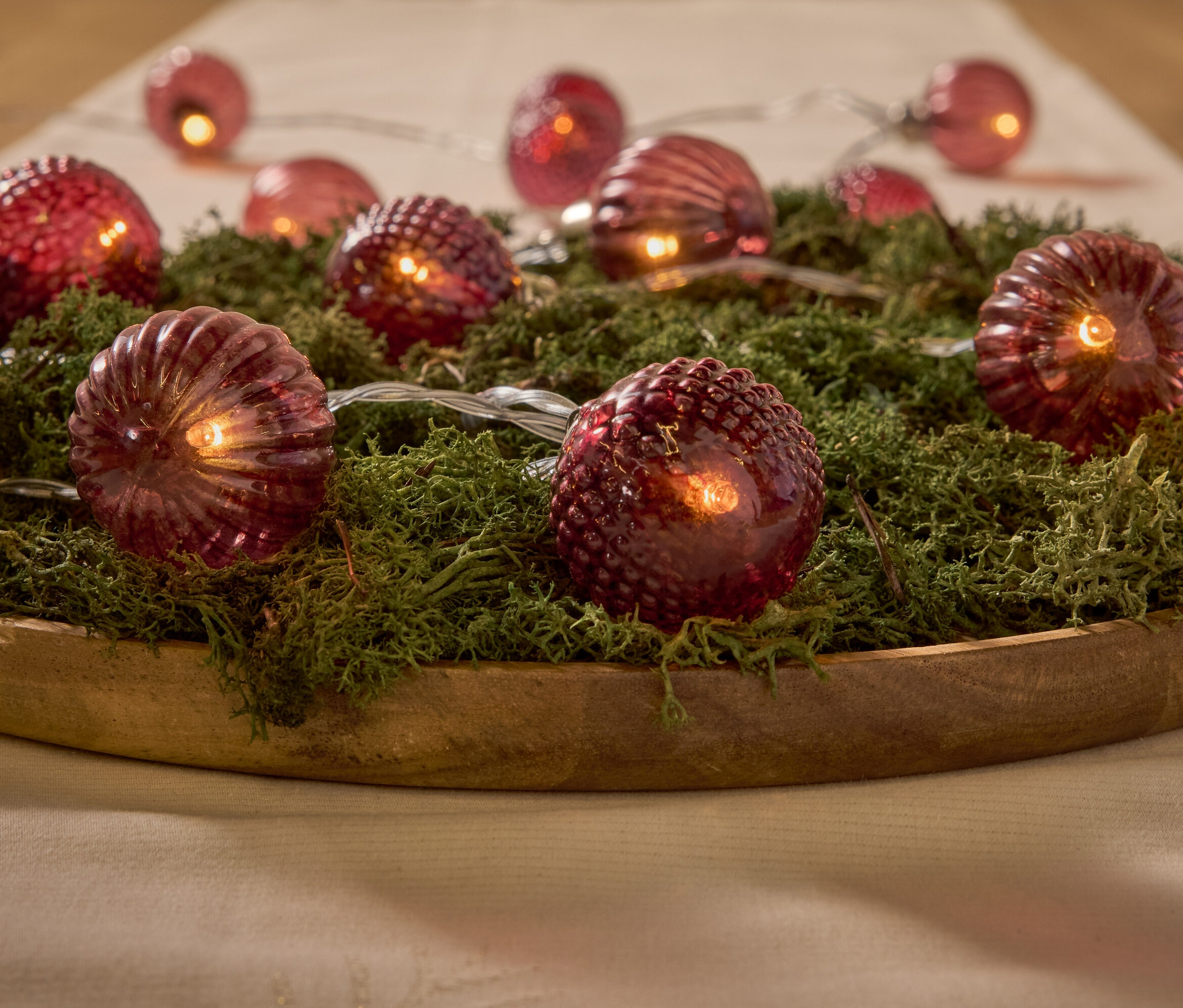 Lumières rouges décoratives sur la mousse dans un bol en bois.
