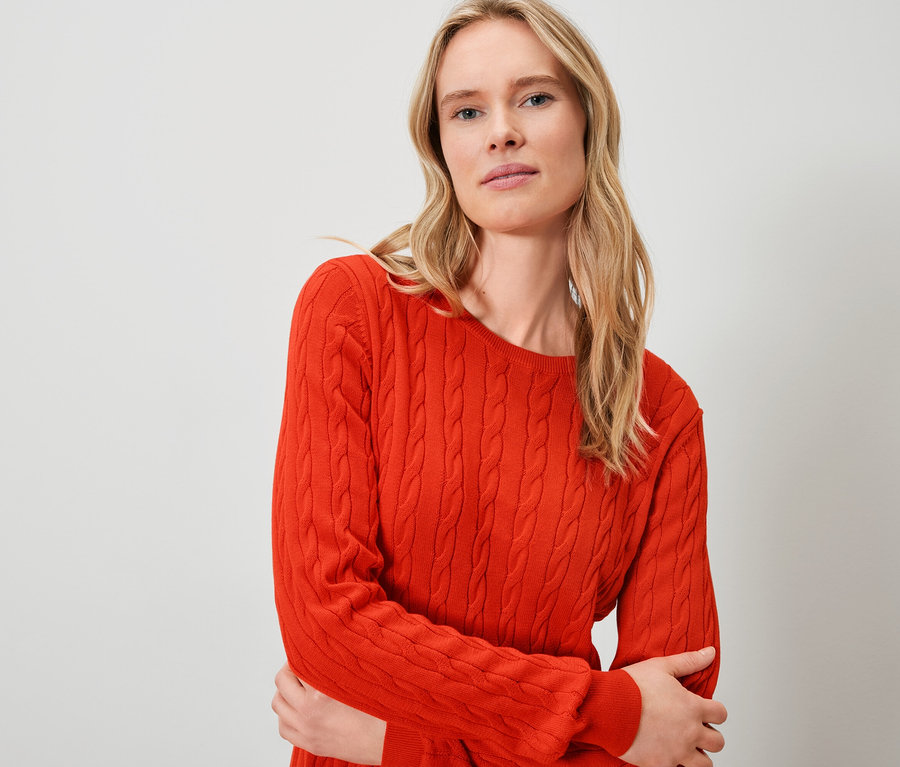 Une femme blonde porte un pull orange.