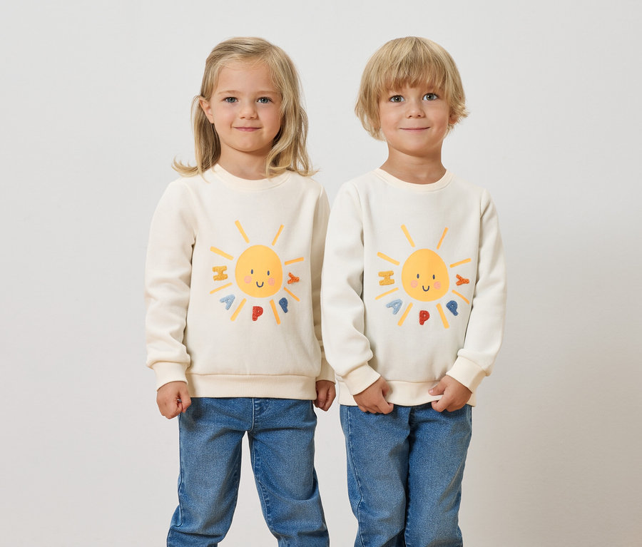 Deux enfants se tiennent côte à côte et portent des sweatshirts pour enfants avec un intérieur gratté et un motif de soleil.
