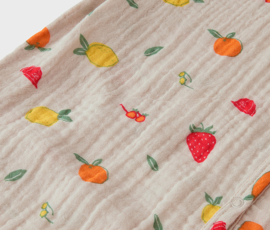 Gros plan d'un tissu à motifs de fruits, notamment des fraises, des citrons et des oranges.