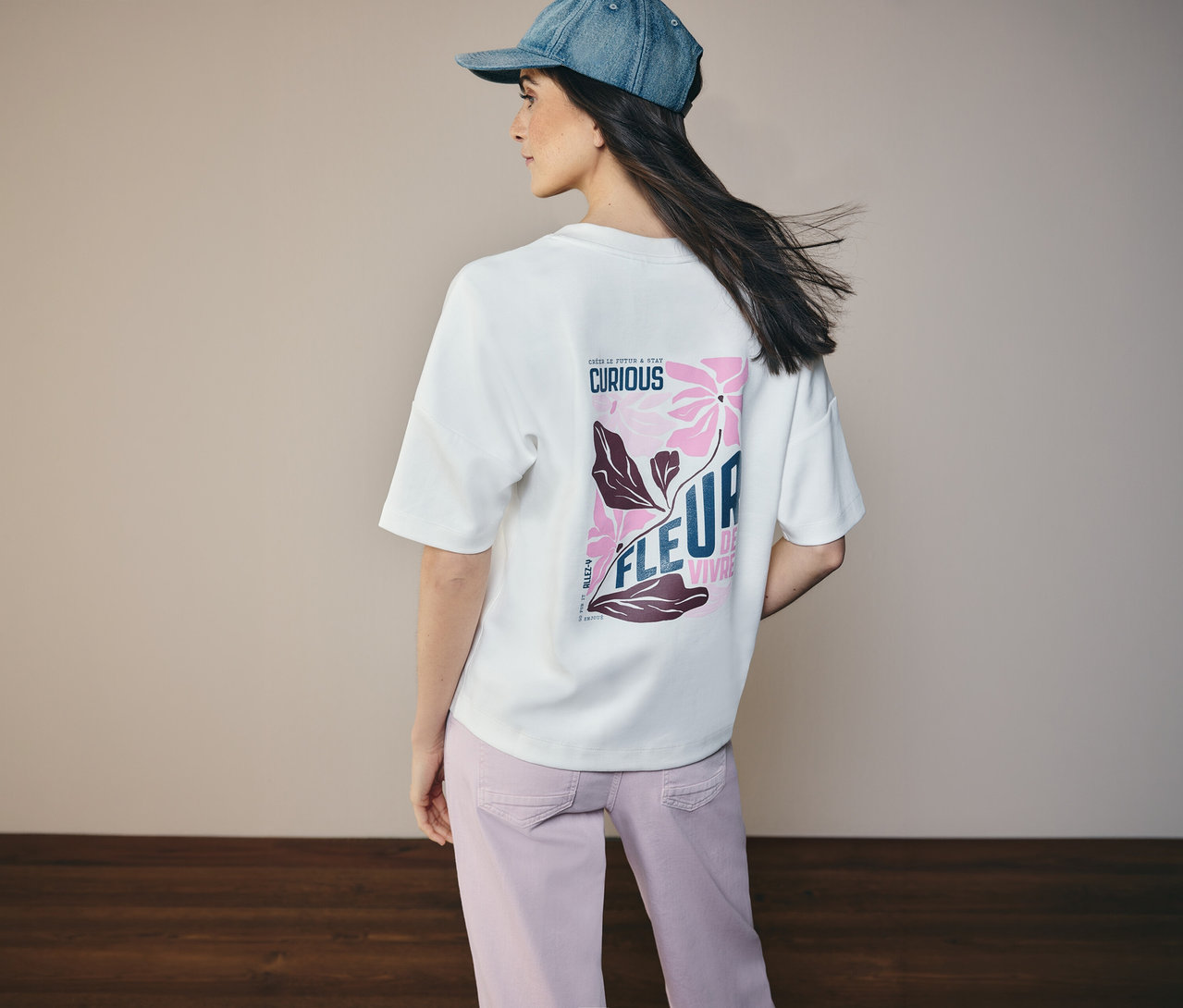 Femme de dos avec une veste en jean et un sweat-shirt CECIL avec un motif floral au dos.