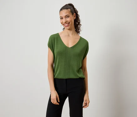 Femme portant un haut vert et un pantalon noir.