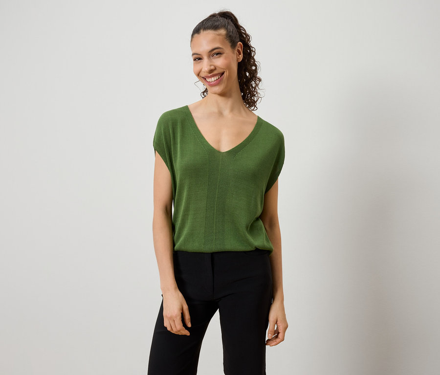 Femme portant un haut vert et un pantalon noir.