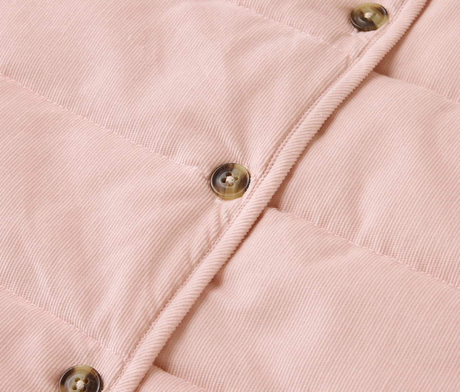 Gros plan sur une veste matelassée rose avec des boutons.