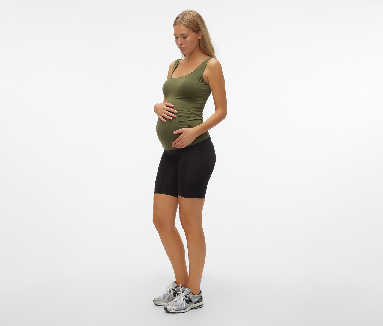 Femme enceinte portant un débardeur vert olive et un Skinny Short MAMALICIOUS «
MLTIA JEANNE », mellow buff, debout de profil.