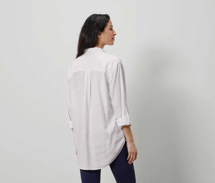 Femme de dos portant une chemise blanche et un legging bleu.