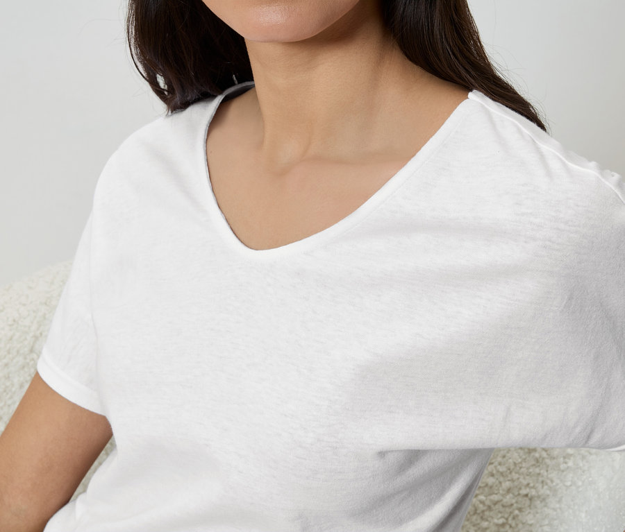 Une femme porte un t-shirt blanc à col en V.