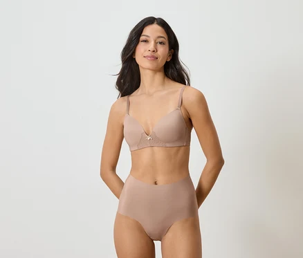 Une femme portant un soutien-gorge et une culotte couleur chair sur un fond blanc.