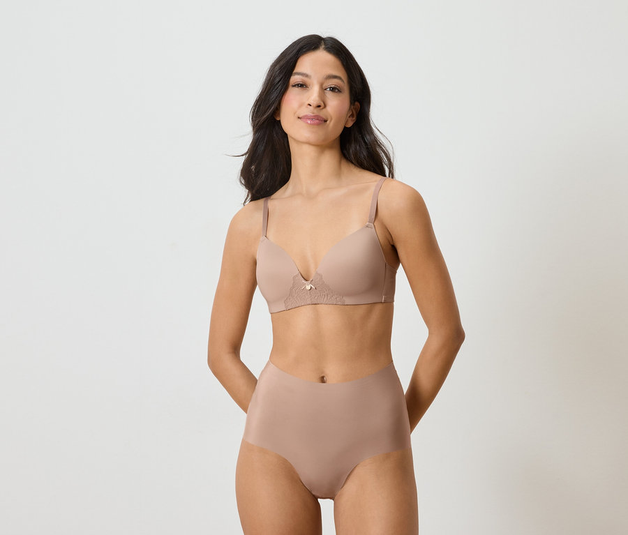 Une femme portant un soutien-gorge et une culotte couleur chair sur un fond blanc.