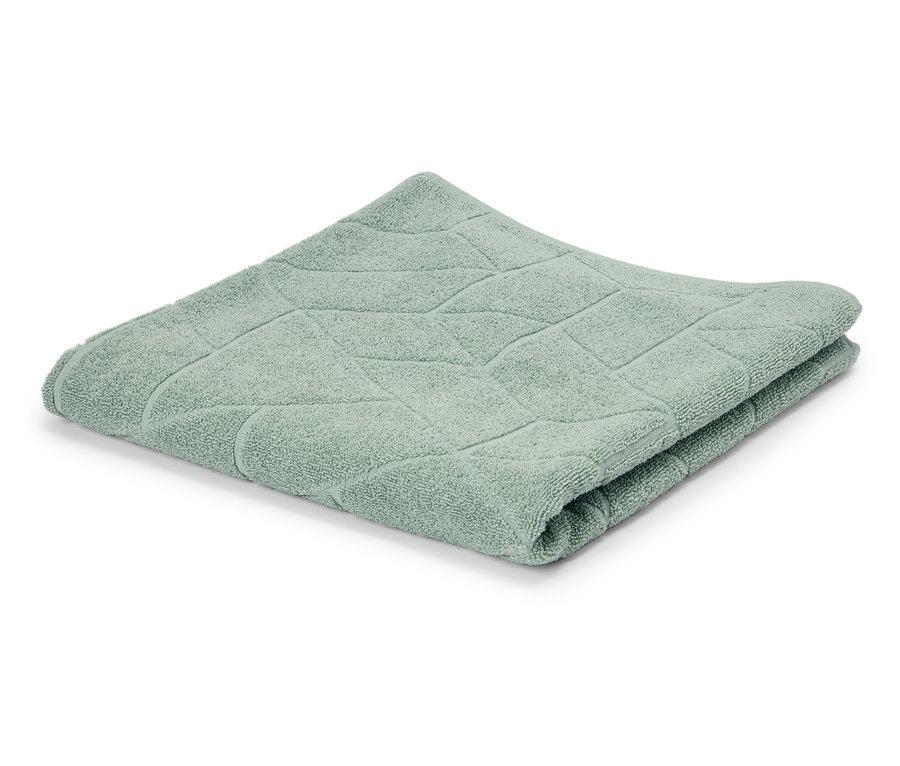Une serviette vert clair pliée avec un motif géométrique sur un fond blanc.