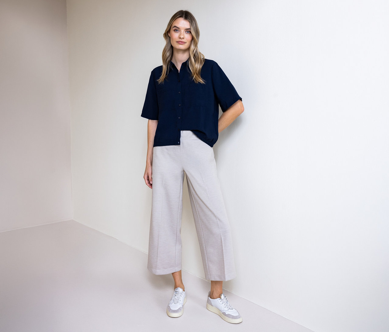 Femme portant un pantalon et un chemisier Street One. Elle se tient devant un mur.