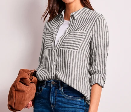 Femme portant un chemisier Street One à rayures marron foncé et blanches, un t-shirt blanc et un jean, tenant une pochette marron.