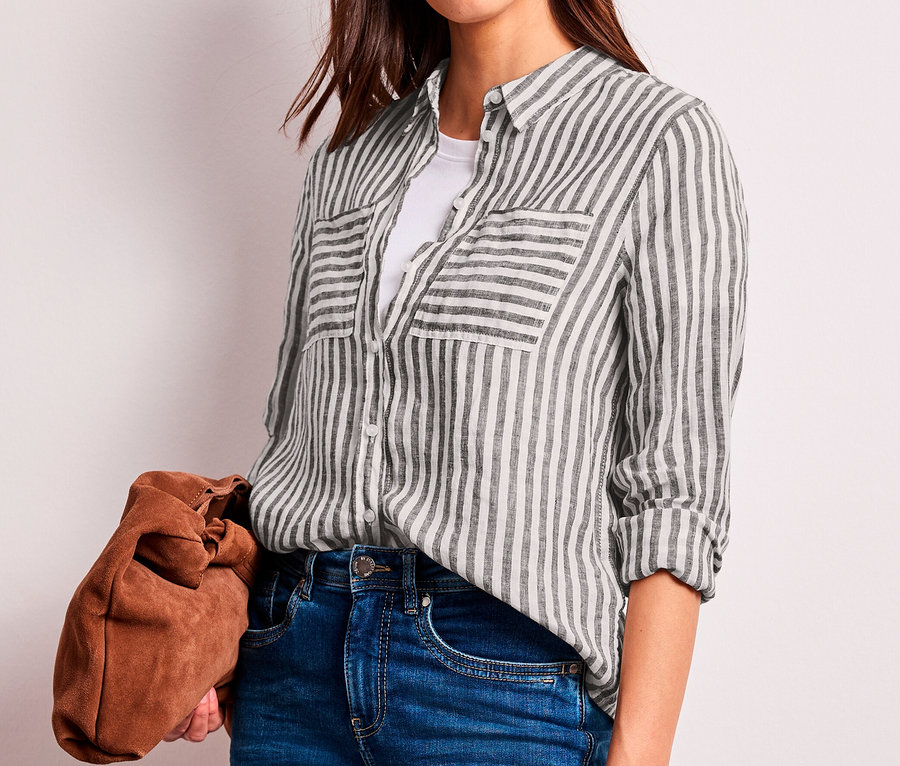 Femme portant un chemisier Street One à rayures marron foncé et blanches, un t-shirt blanc et un jean, tenant une pochette marron.