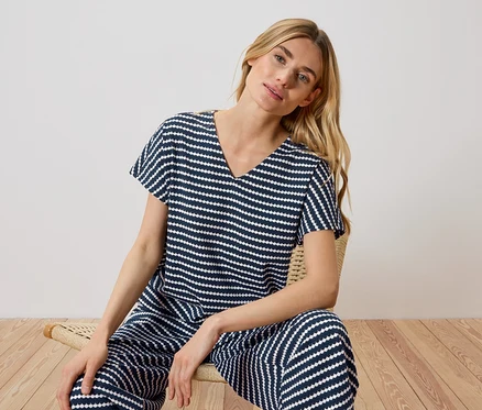 Une femme blonde est assise sur une chaise et porte un pyjama rayé bleu marine et blanc.