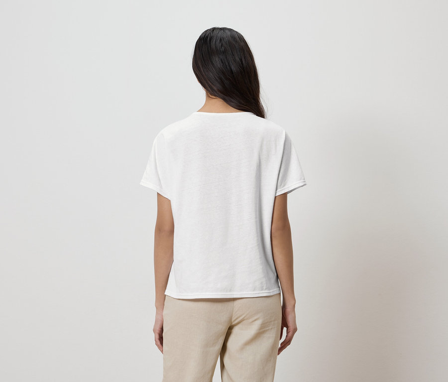 Vue arrière d'une femme aux longs cheveux noirs portant un t-shirt blanc et un pantalon beige.