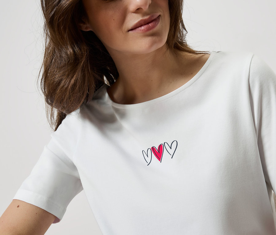 Femme portant un t-shirt blanc avec trois cœurs.