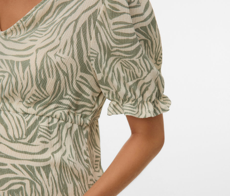 Gros plan d'une femme portant une robe à motif zébré vert.