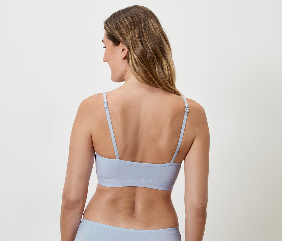 Vue arrière d'une femme aux cheveux longs portant un soutien-gorge bleu clair à bretelles et des sous-vêtements assortis.