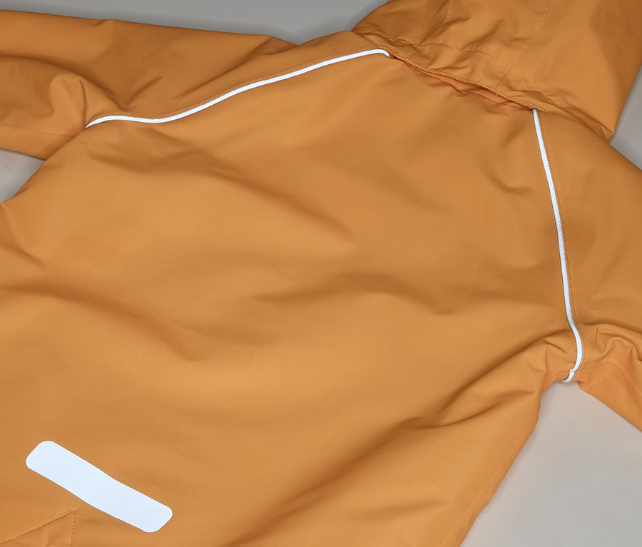 Gros plan sur un imperméable orange avec capuche et réflecteurs blancs.