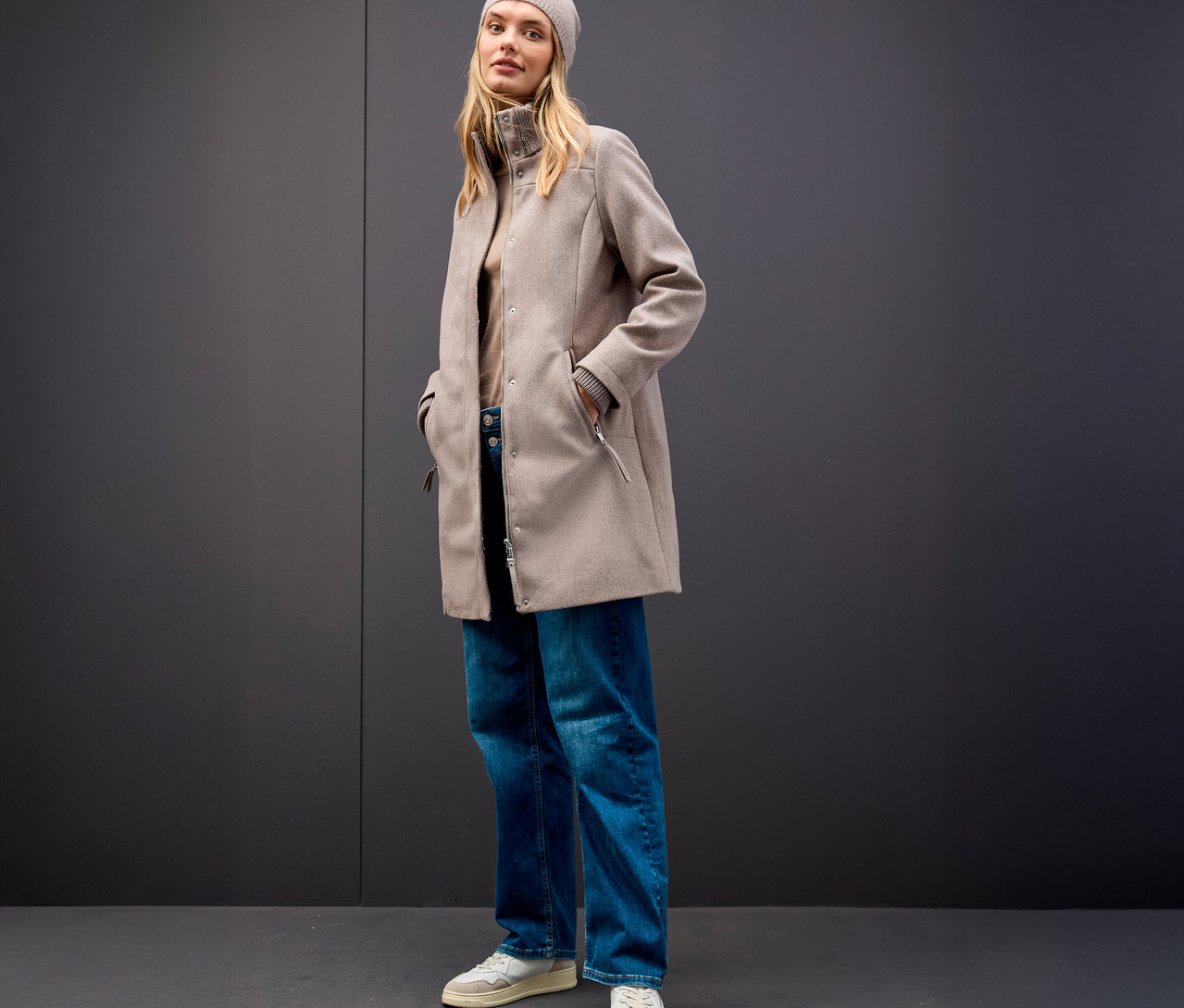 Femme portant un bonnet beige et un manteau court Street One sur fond gris.