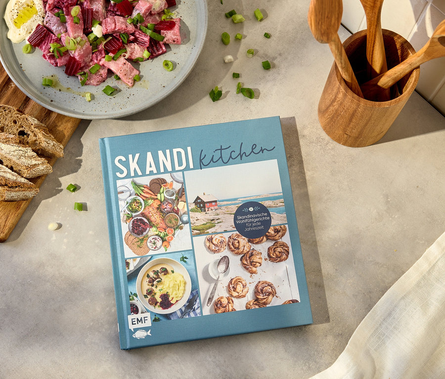 Photo d'un livre de cuisine intitulé 'Skandi Kitchen' à côté d'une assiette de salade de betteraves, de pain et d'ustensiles de cuisine.