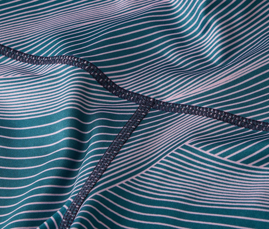 Gros plan sur le tissu des leggings avec des rayures turquoise et blanches et des coutures foncées.