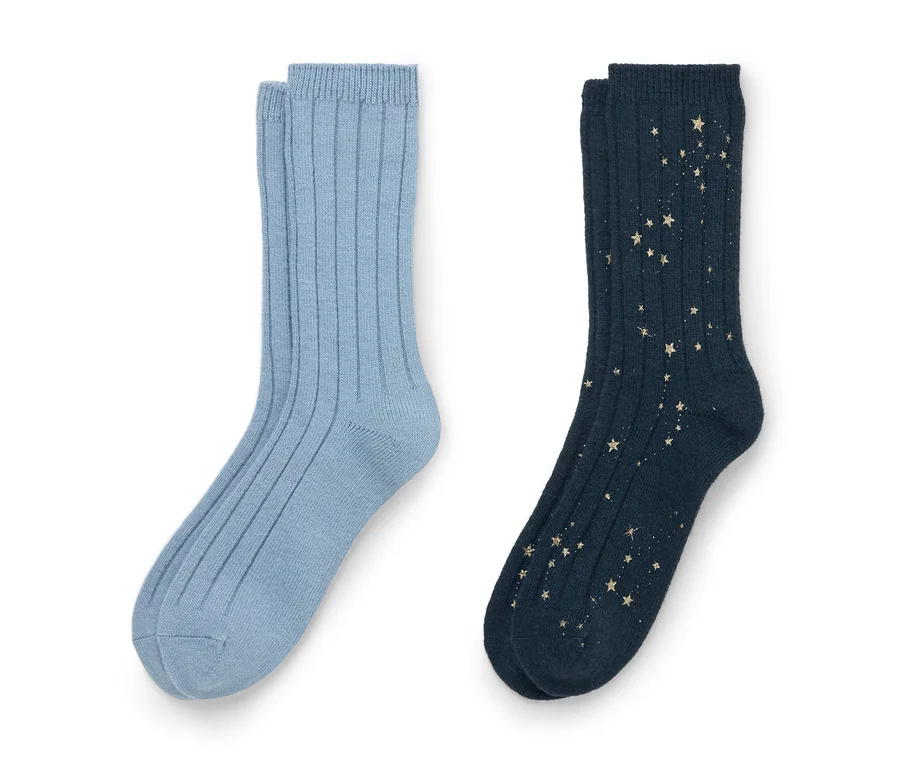 Deux paires de chaussettes côtelées sur fond blanc. La paire de gauche est bleu clair. La paire de droite est bleu foncé avec un motif d'étoiles dorées dispersées.