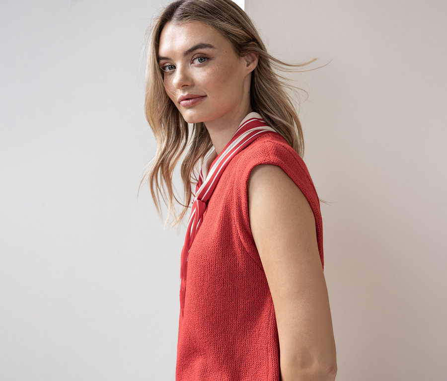 Femme portant un haut sans manches en tricot rouge avec un col rayé.